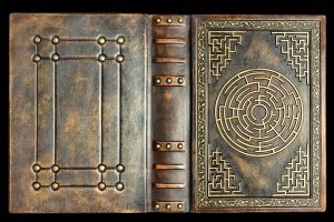 Aged brown leather book cover with labyrinth on the front cover. Captured opened and with black background.